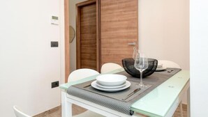 Un coin repas avec une table dressée pour deux personnes, une porte en bois en arrière-plan et un design moderne.