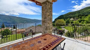 Un balcon agrémenté d’un pilier en pierre, d’une table carrelée et offrant une vue sur un paysage montagneux.