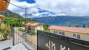 Un balcon offrant une vue sur une chaîne de montagnes et un village situé en contrebas.