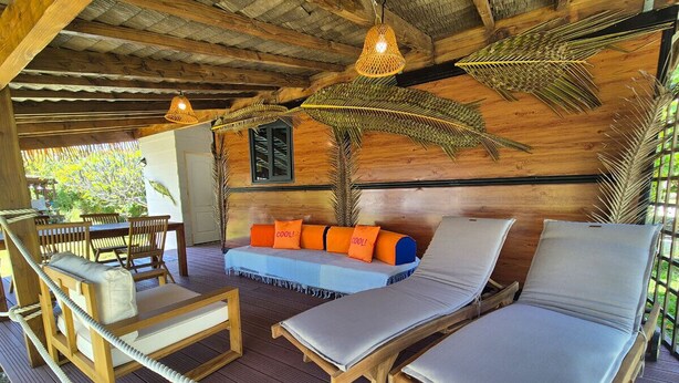 A wooden deck with lounge chairs and a sofa with orange cushions. - Moana Breeze Eco Lodge (Rangiroa)