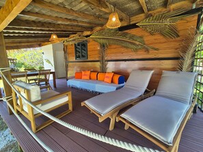 Une terrasse en bois avec des chaises longues et un canapé doté de coussins orange.
