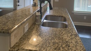 A kitchen with granite countertops, a stainless steel sink, and a pendant light.