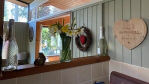 Et køkken med træhylder, en vase med blomster, et hjerteformet skilt og en champagneflaske.