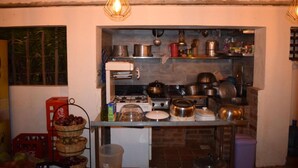 A kitchen with a gas stove, shelves with pots and pans, and a hanging light fixture. - Kileefarm Cottages (Nguluni)