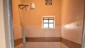A small, tiled shower room with a window, a towel rack, and a red mat on the floor. - Kileefarm Cottages (Nguluni)
