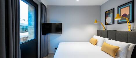 A modern hotel room with a large bed, a flat-screen TV, and two bedside lamps.