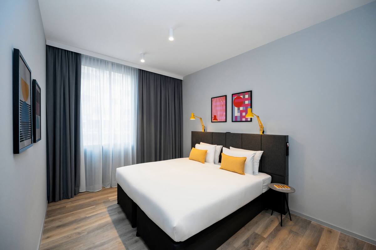 A modern hotel room with a large bed, a bedside table, and a nightstand.