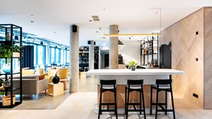 Decoração moderna com área de bar central, assentos e uma grande janela que oferece luz natural.