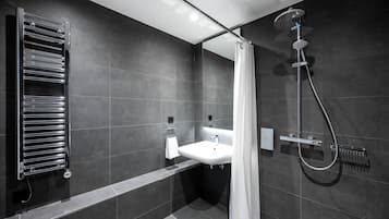 Un baño moderno con ducha integrada, toallero y lavamanos.