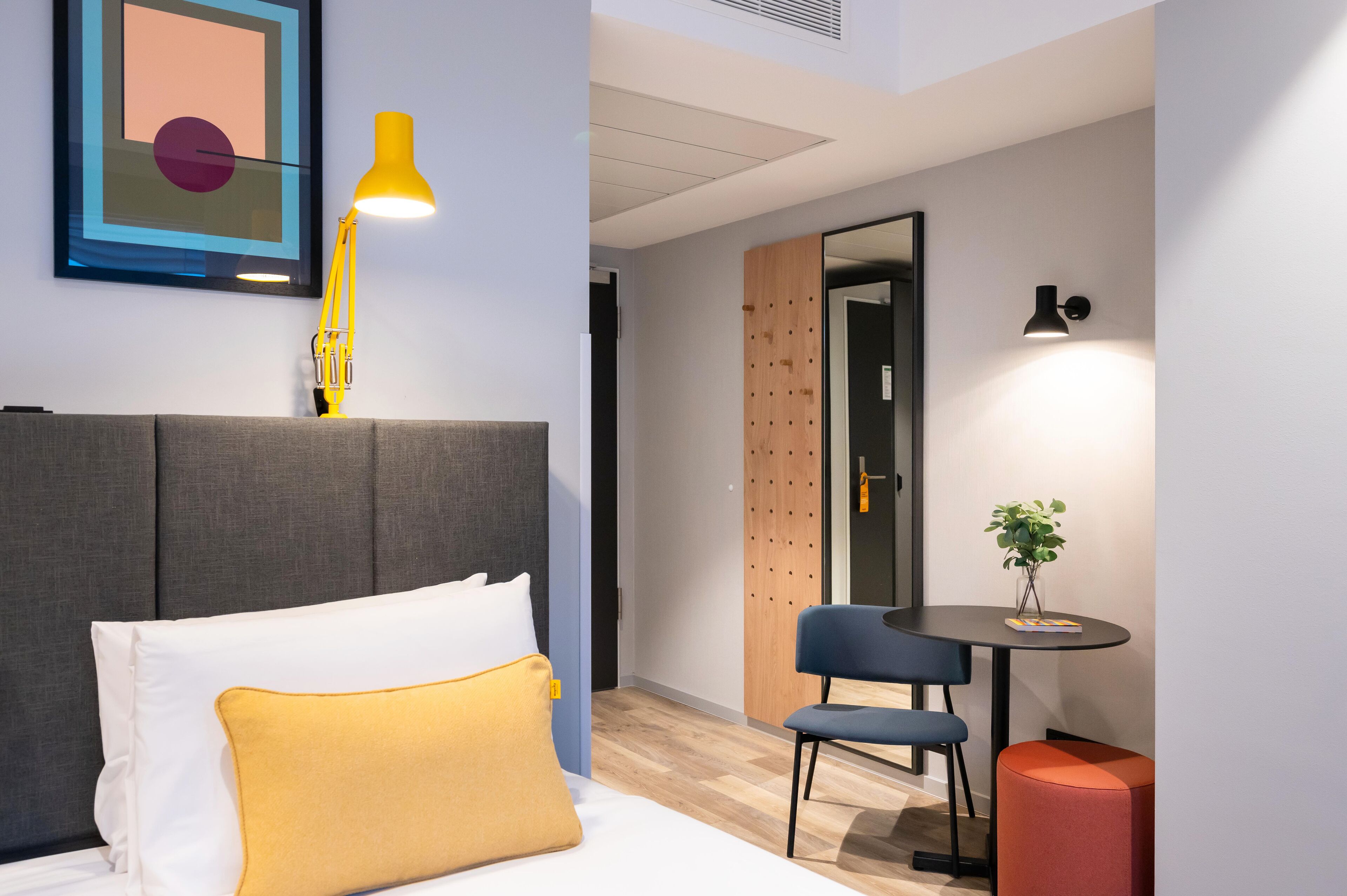 Ein modernes Hotelzimmer mit Bett, Schreibtisch und Stuhl.