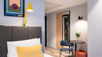 Ein modernes Hotelzimmer mit Bett, Schreibtisch und Stuhl.
