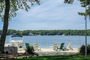 Une terrasse au bord du lac, avec des chaises, une table et un bateau amarré.