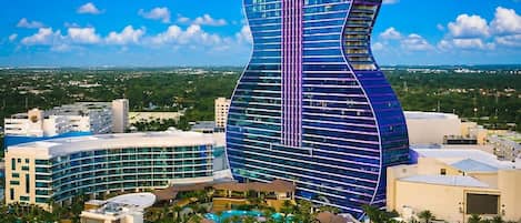 Um resort com um edifício em formato de guitarra, várias piscinas e um cenário tropical.