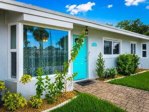 A single-story building with a blue door, numbered 110, and a small porch area.