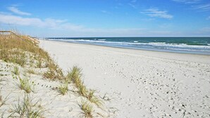 Une plage de sable avec une promenade en bois qui mène à l’eau.