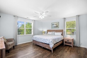 A bedroom with a bed, nightstand, chair, and a ceiling fan. - Private Pool Beach House, Easy Walk to Beach, 2 Screened Porches, Dog Friendly (Pawleys Island)