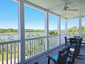 A covered outdoor area with a view of a lake, dock, and distant buildings.