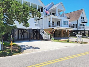 A two-story building with a porch, a flag, and a sign indicating it's a real estate office.
