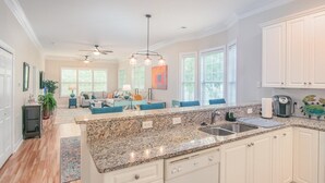 A spacious kitchen with granite countertops, white cabinetry, and a central island.