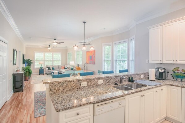 A spacious kitchen with granite countertops, white cabinetry, and a central island.