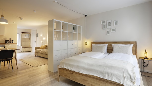 Et moderne soveværelse med en træseng, et hvidt skab og et spiseområde med bord og stole.