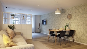 En moderne stue med sofa, spisebord med stole, et TV ophængt på væggen og et dekorativt ur.