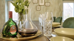 Et spisebord med en flaske Juliusspital vin, en vase med blomster og flere vinglas.