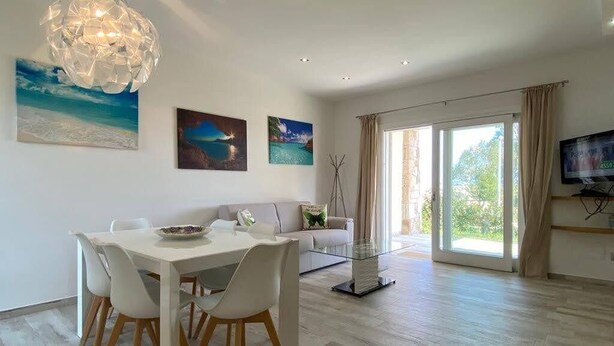 A modern living room with a dining area, large windows, and artwork on the walls. - R House 2 independent semi-detached house (Budoni)