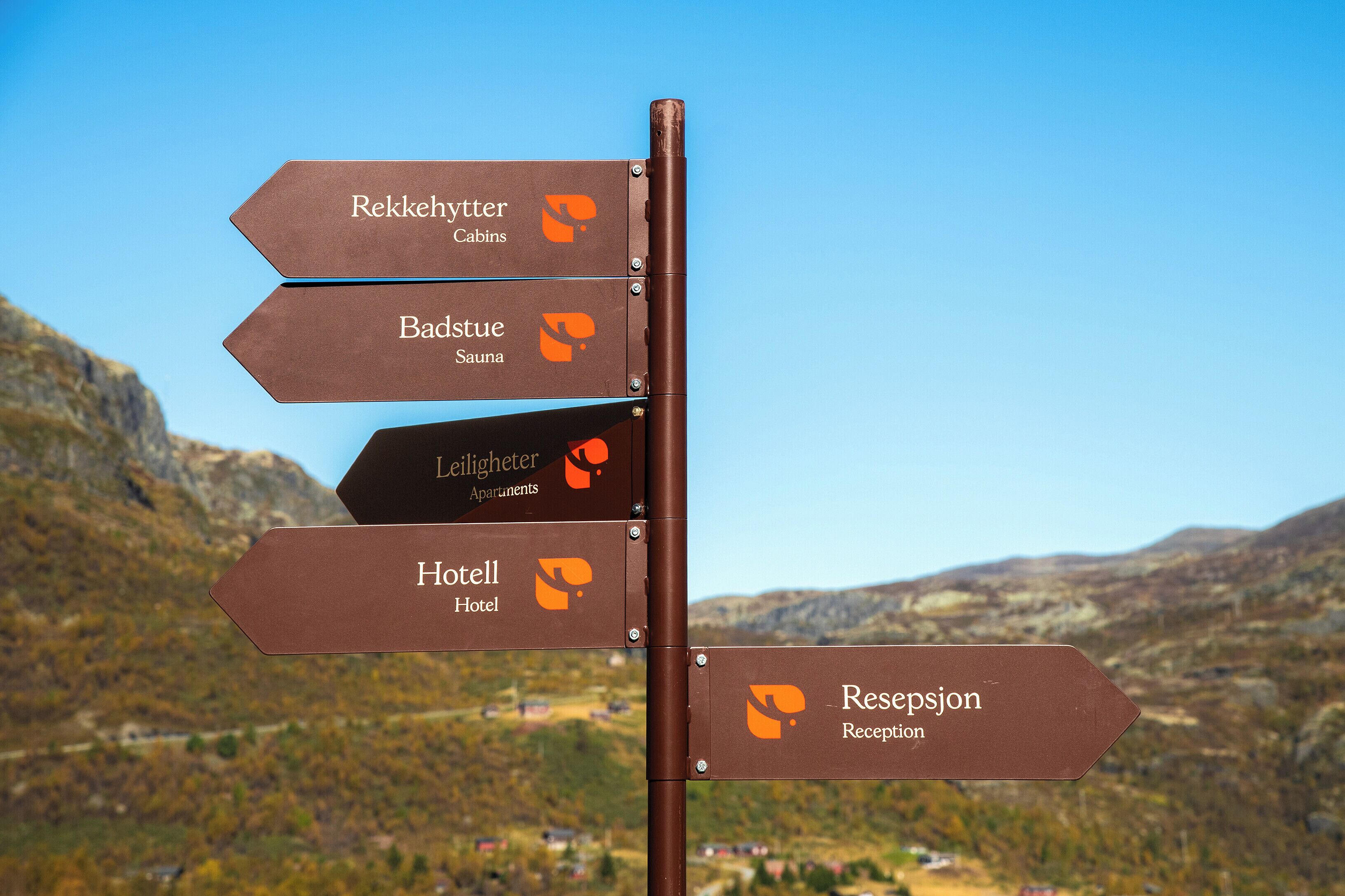A directional sign with arrows pointing to various accommodations including cabins, apartments, a hotel, and a reception area.