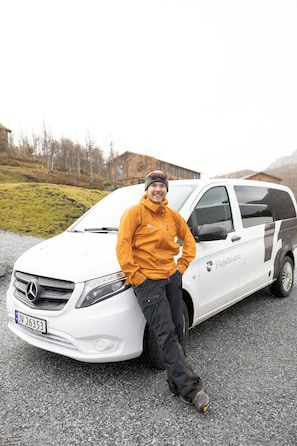 A person standing next to a white vehicle with a license plate and a logo on the side.