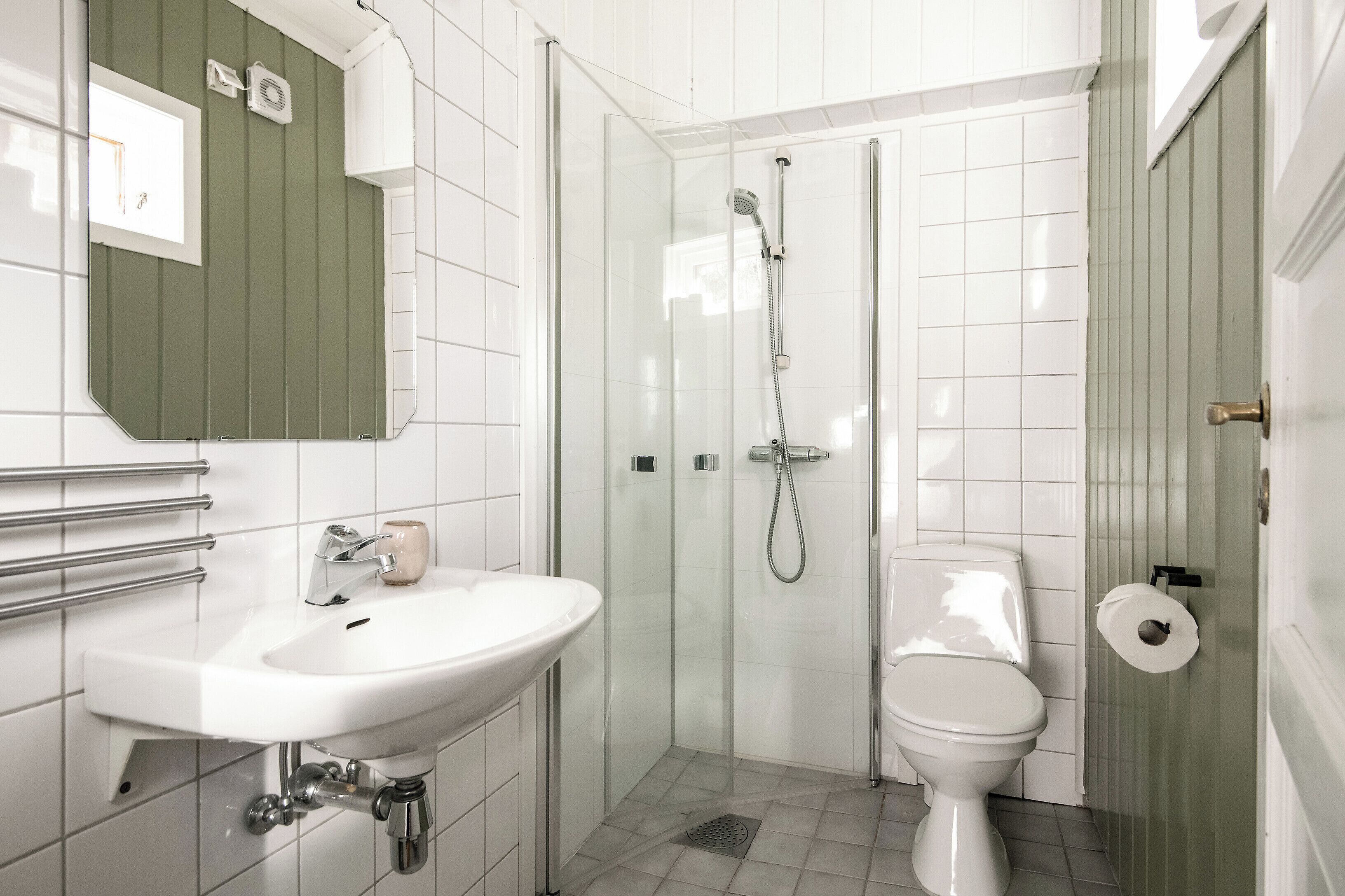 A bathroom with a white sink, toilet, and glass-enclosed shower.