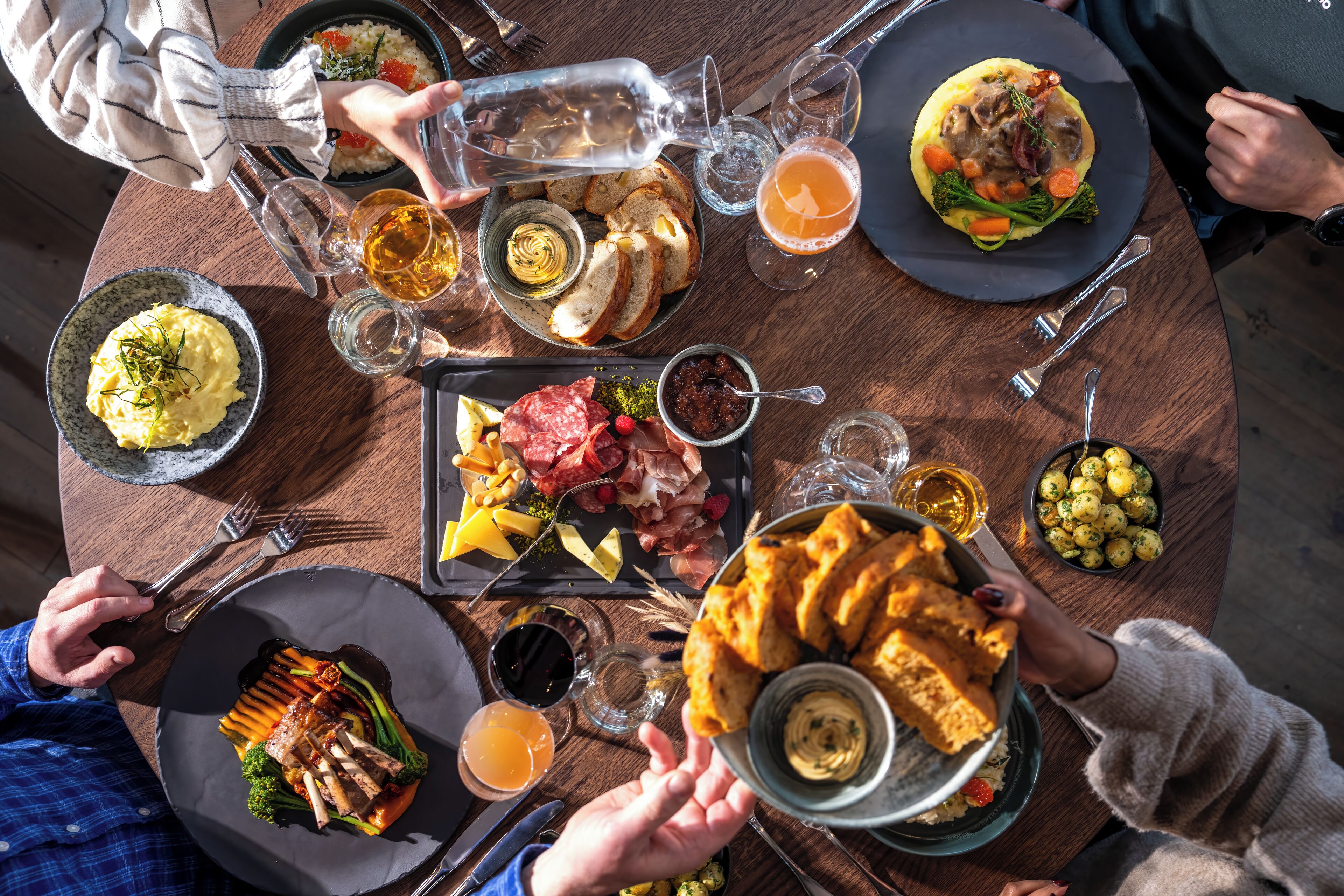 Una mesa redonda para comer con diferentes platos, bebidas y cubiertos.