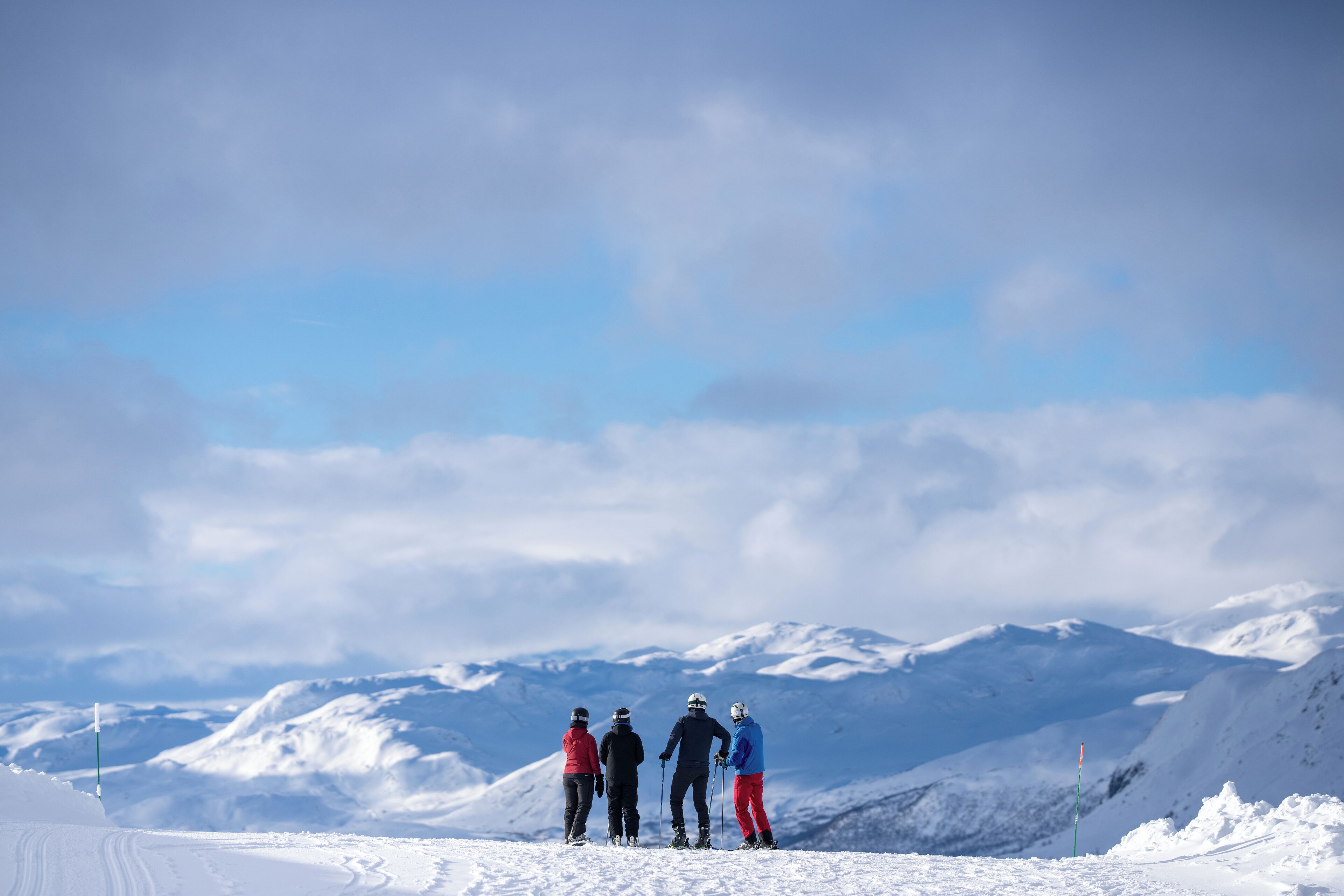 Un grupo de personas de pie en una montaña nevada con cielo despejado.