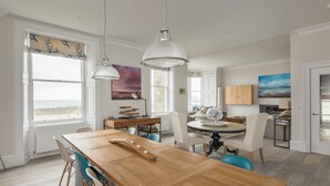 A spacious dining area with a wooden table, chairs, and pendant lighting. - A 4-bedroom luxury holiday home with enchanting sea views across Milsey Bay Beach (North Berwick)