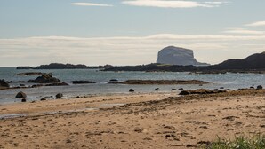 A beach with rocky outcrops and a large rock formation in the distance. - A 4-bedroom luxury holiday home with enchanting sea views across Milsey Bay Beach (North Berwick)