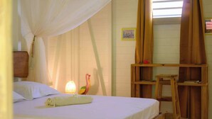 Un dormitori amb un llit, una làmpada de nit, una escala de fusta i una finestra amb cortines.