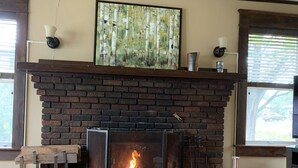 A fireplace with a fire, a wooden mantel, and a painting above it. - Stately home in Washburn  (Washburn)