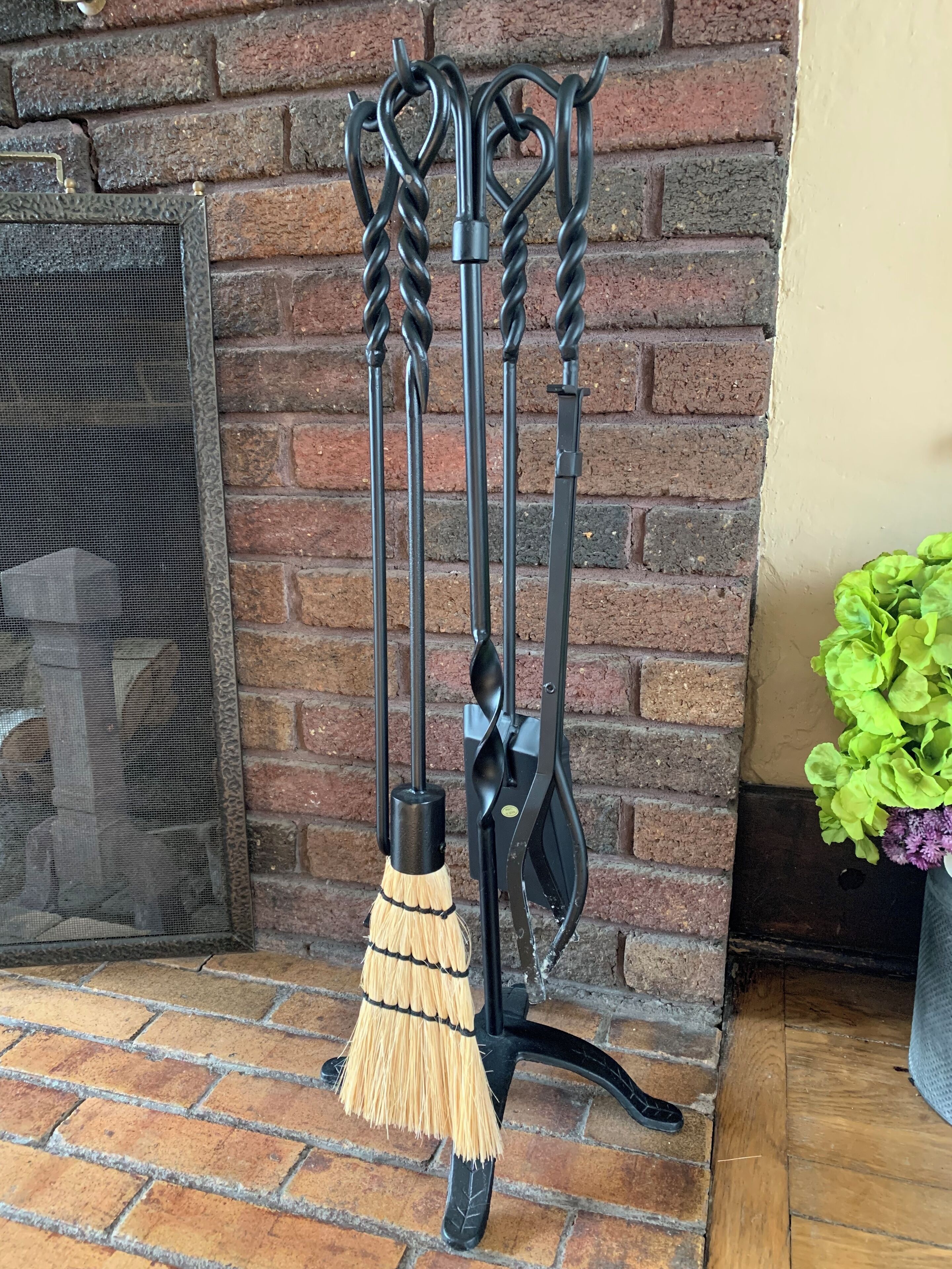 A fireplace with a metal screen, a brick wall, and a broom leaning against it.