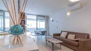 Een moderne woonkamer met een bank, een salontafel en een decoratieve vaas met takken.