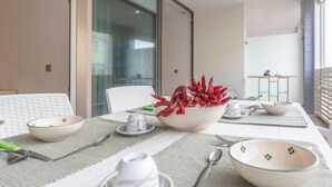 Een eethoek met een tafel voor vier personen, inclusief kommen, bestek en een decoratieve plant.