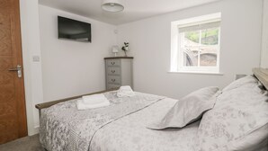A bedroom with a bed, a dresser, a TV, a window, and a door. - 1 The Riverside (Barnard Castle)