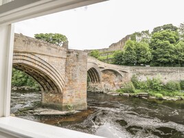 Un puente de piedra sobre un río, con una vista de un castillo al fondo.