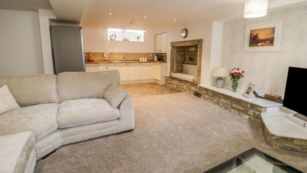 A living room with a sofa, a TV, and a kitchen in the background. - 1 The Riverside (Barnard Castle)