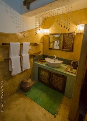 A bathroom with a sink, mirror, hanging light fixture, and towels on a rack. - Zawadi Residence (Watamu)