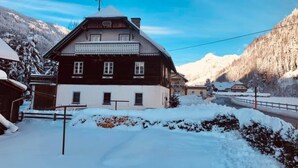 A traditional wooden house with a sloped roof, surrounded by snow-covered mountains and a clear sky. - Rösslgut (Zederhaus)