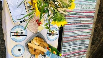 Ein Tisch gedeckt mit Tellern, Besteck, Brot und verschiedenen Snacks und Früchten.