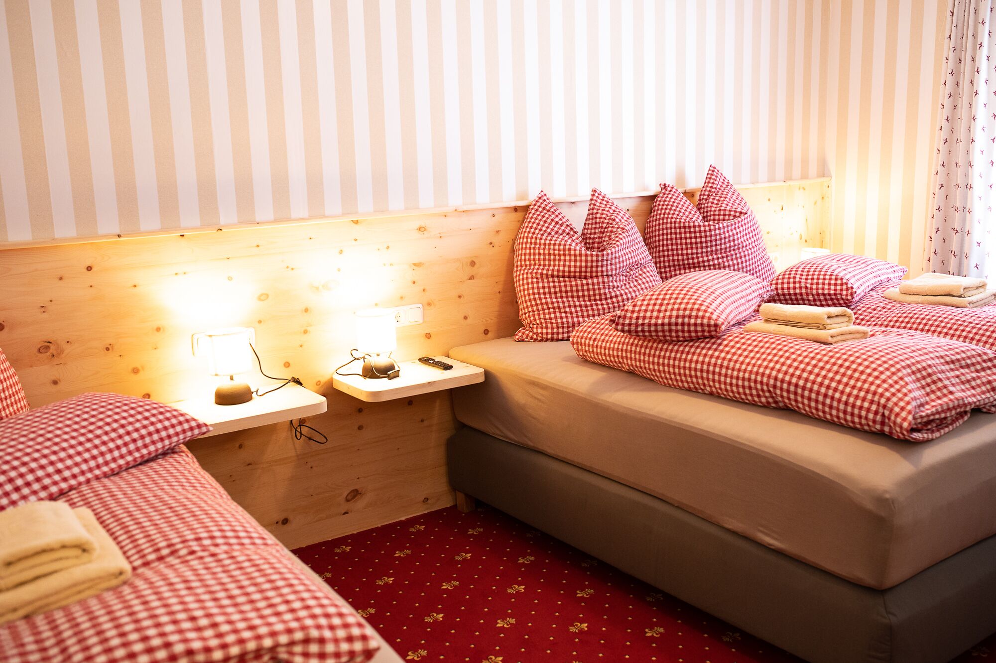 A cozy room with a bed, bedside tables, and a red carpet.