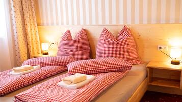 A double bed with checkered bedding and pillows, two bedside tables with lamps, and a striped wall.