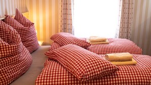A hotel room with checkered bedding, a bed with two towels, and striped curtains. - Rösslgut (Zederhaus)