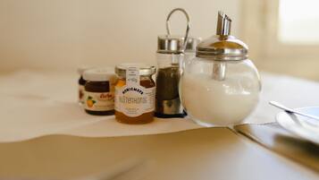A table with three jars of honey and a sugar bowl.